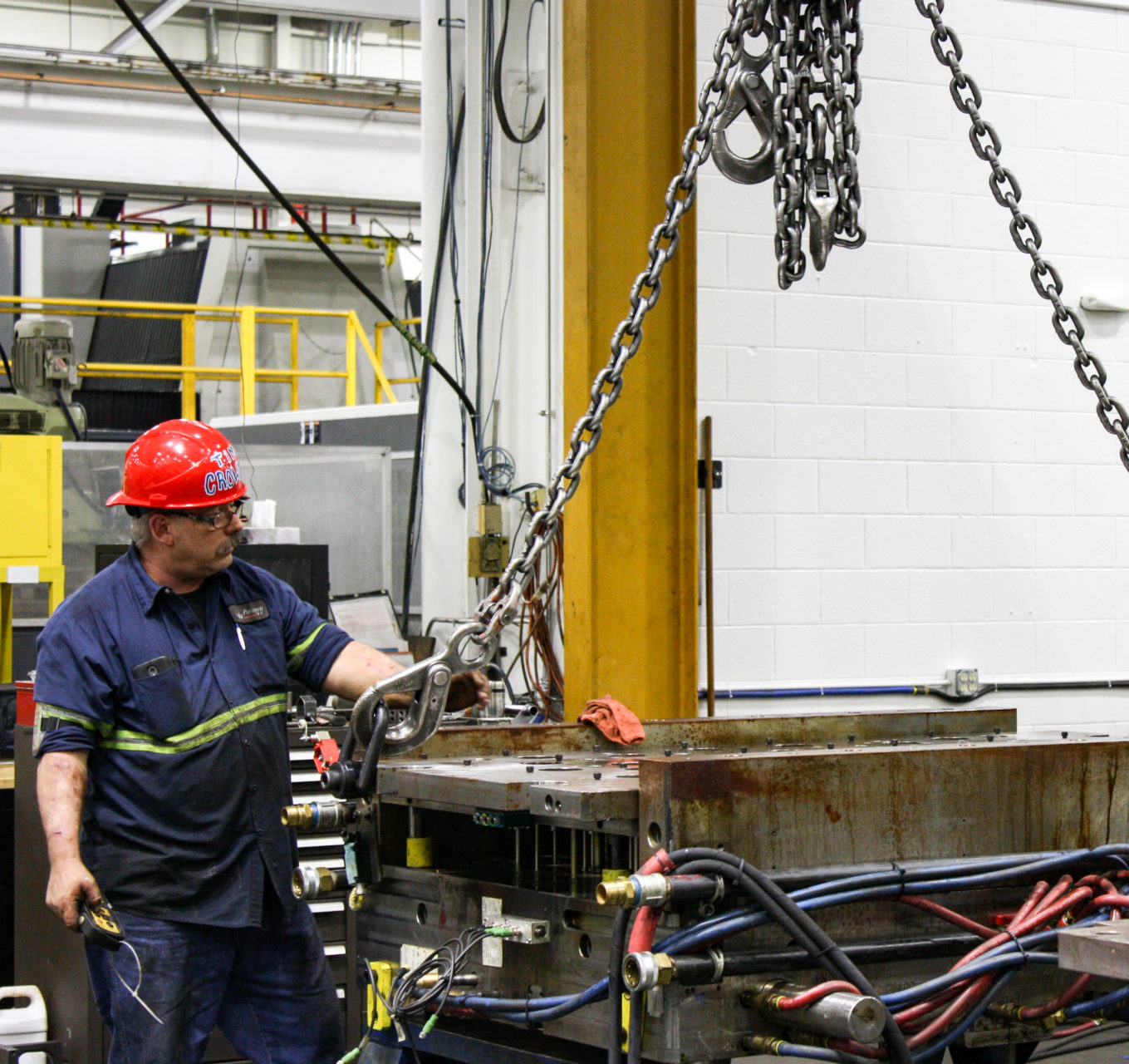 employee wearing hardhat working with injection mold equipment